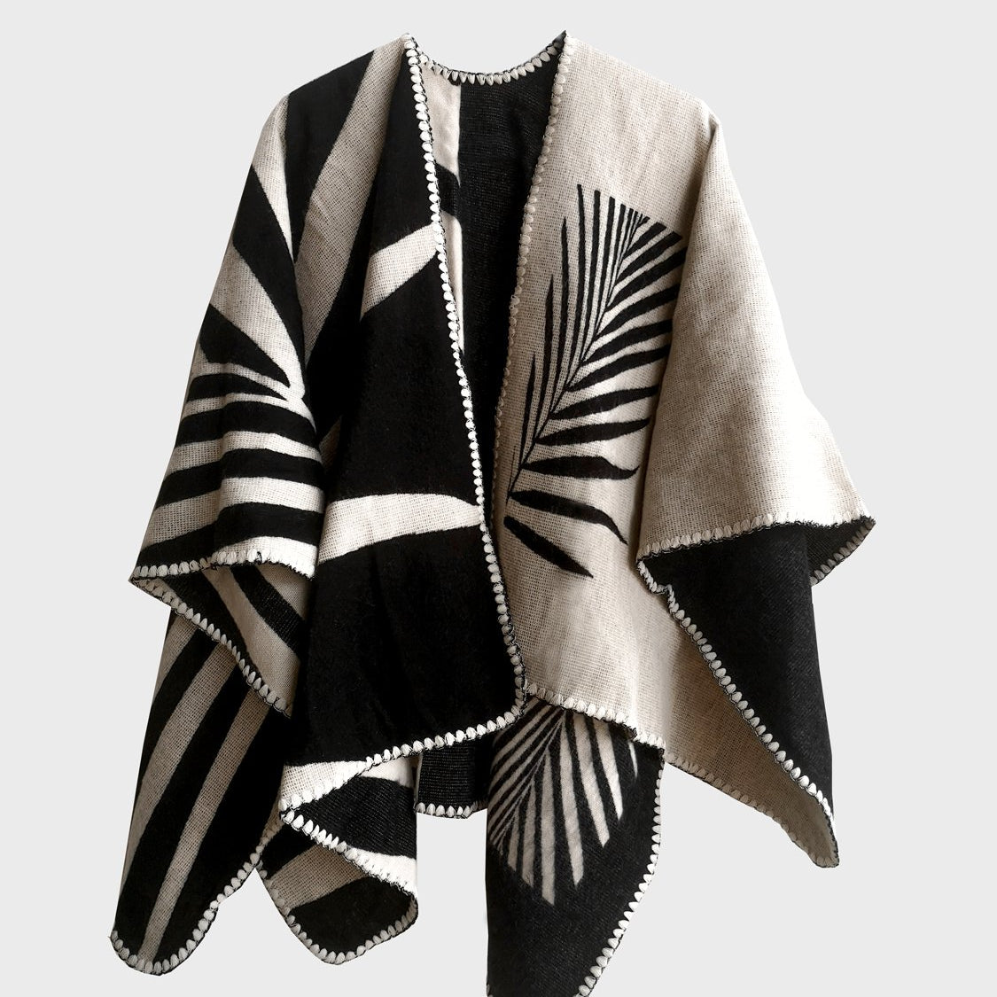Natura Poncho on a white background. This poncho features a color block design with leaflike pattern on the darker half. On the lighter half is ti just a small rectangle box of a leaf.