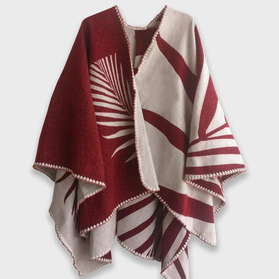 Red Natura Poncho on a white background. This poncho features a color block design with leaflike pattern on the darker half. On the lighter half is ti just a small rectangle box of a leaf.