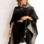 Women wearing the OX Black and Grey Poncho without the hood. She paired the poncho with a brown hat, light brown top, and black jeans.