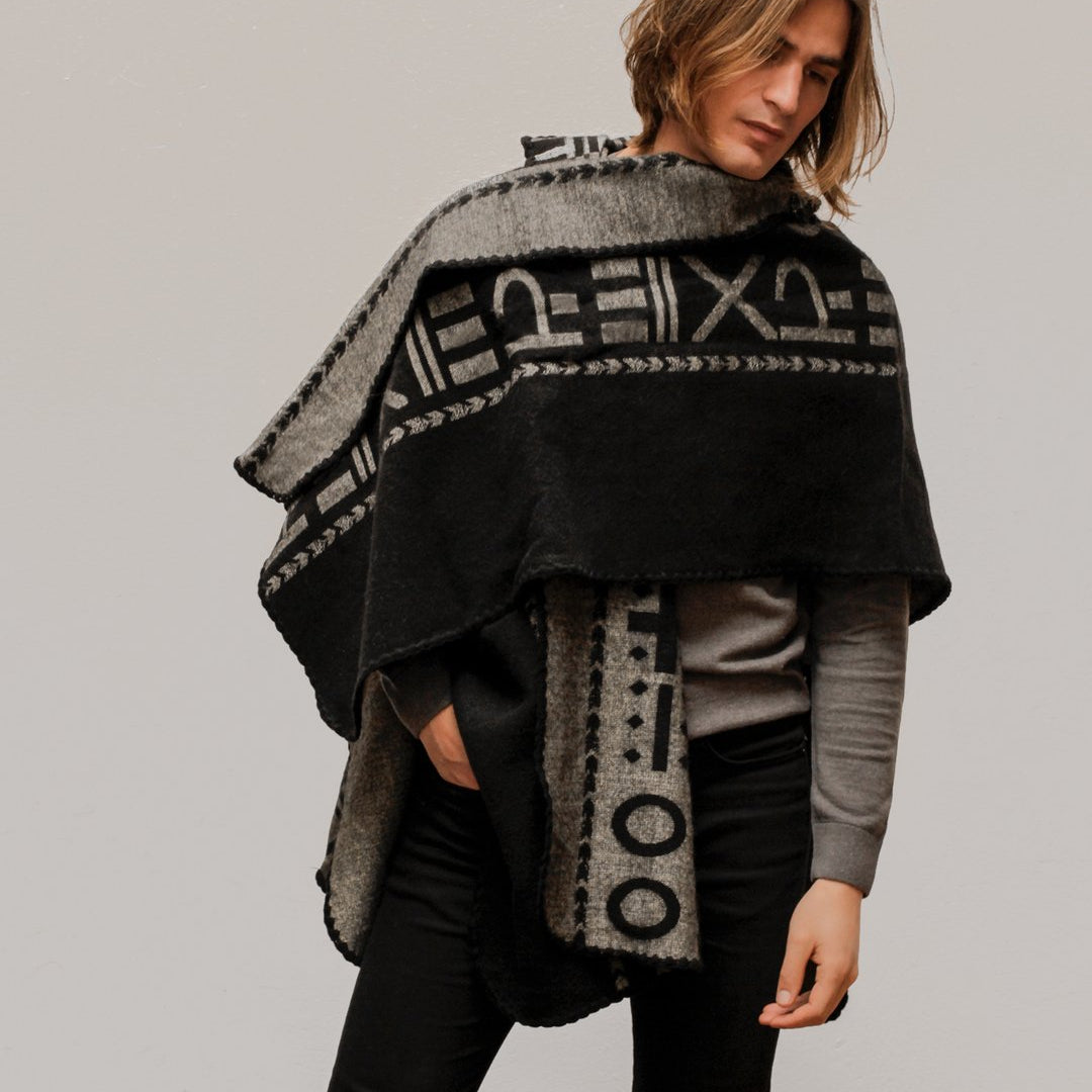 Man wearing the OX Black and Grey Poncho with Hood. He paired it with a grey top and black jeans. He is over a plain grey background.