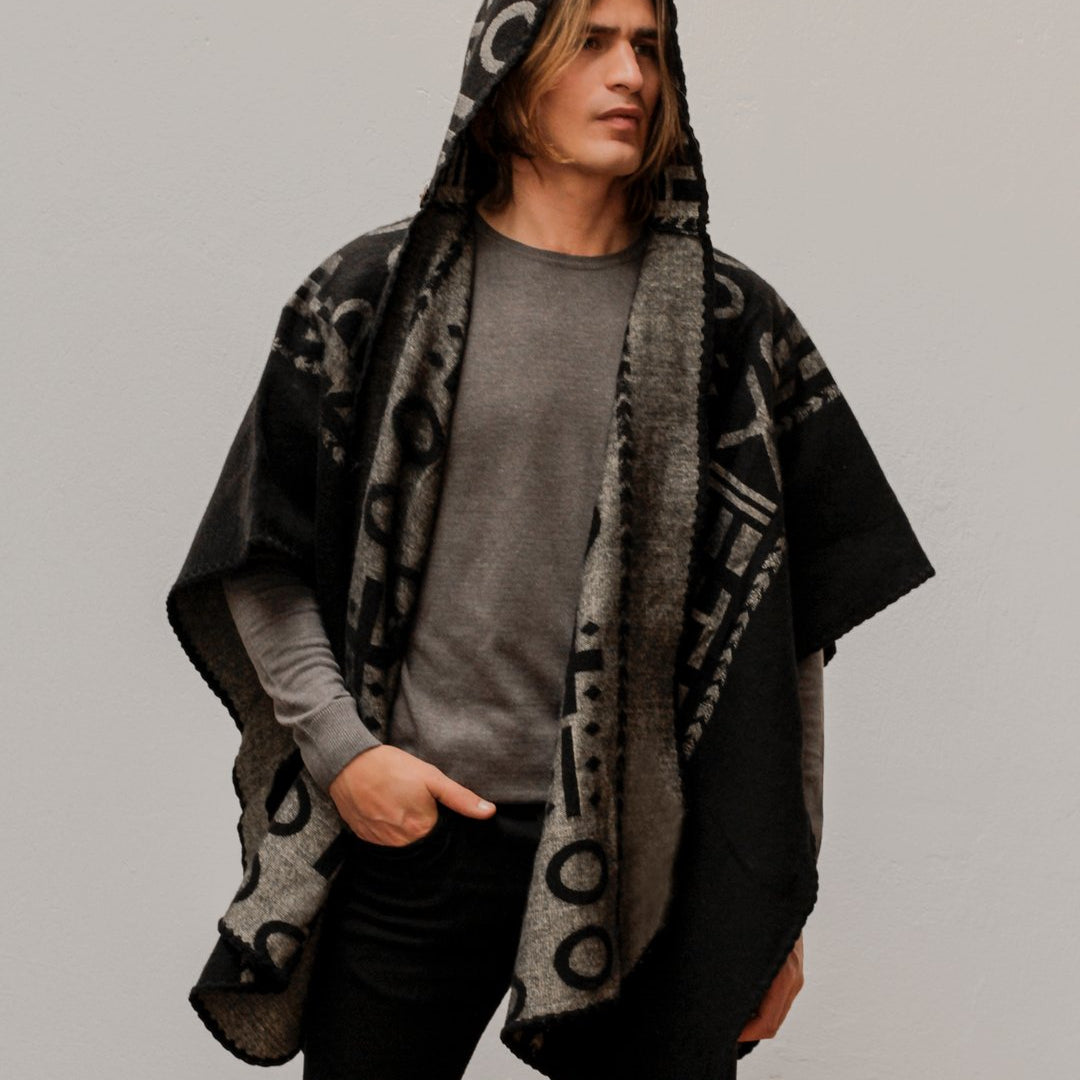 Man wearing the OX Black and Grey Poncho with Hood. He paired it with a grey top and black jeans. He is over a plain grey background.
