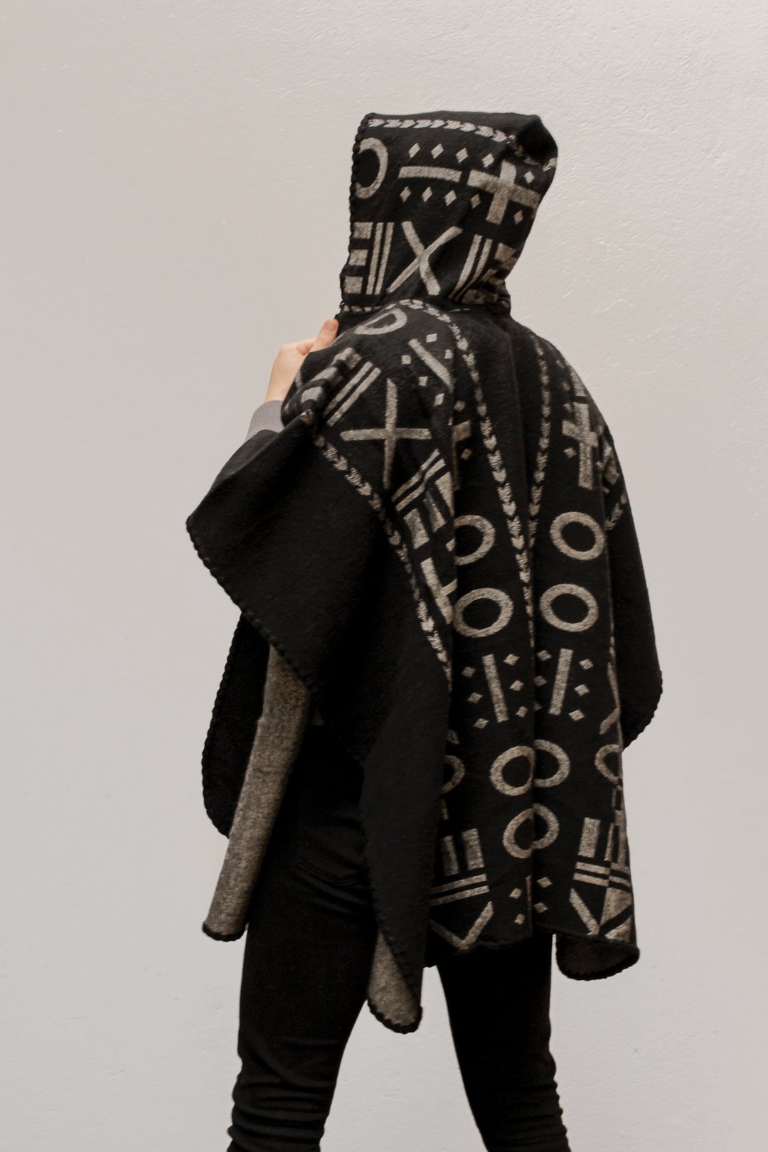 The back of the model wearing the OX Black and Grey Poncho with Hood over a plain background.