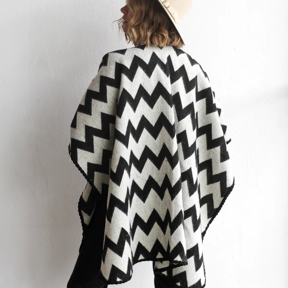 Back of woman modeling the picos ponchos. The pattern features a zig zag pattern across the whole poncho. She wore it with a light brown hat, cream top, and black jeans.