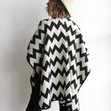 Back of woman modeling the picos ponchos. The pattern features a zig zag pattern across the whole poncho. She wore it with a light brown hat, cream top, and black jeans.