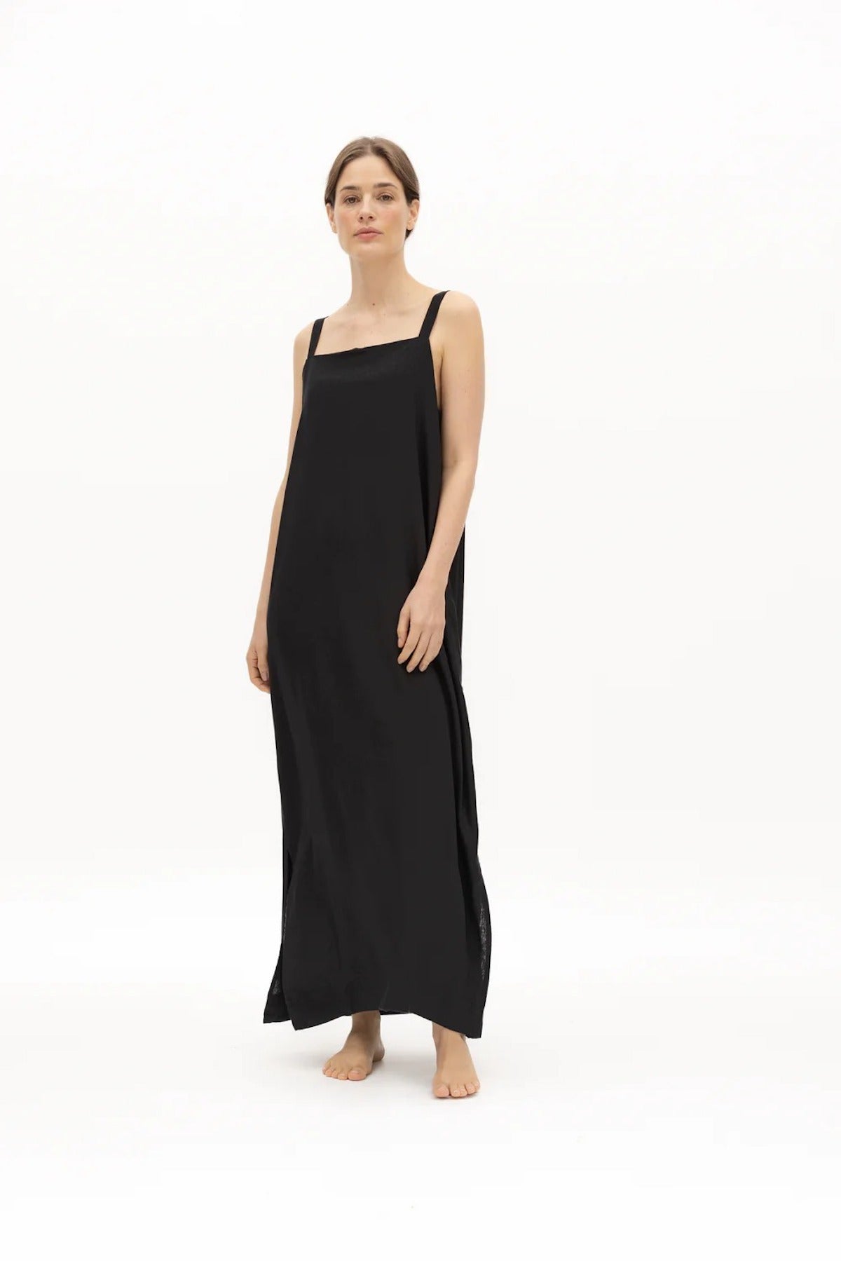 Image of a woman wearing a long dress with pockets and spaghetti straps that was made in Colombia by NAOS. The purpose of this image is to highlight the dress, which is for sale at EVAMAIA boutique in Studio City, CA and online.