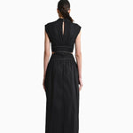Back of Model wearing Toya Maxi Dress with Side Cutouts, mockneck and gold stitching around waist on plain white background