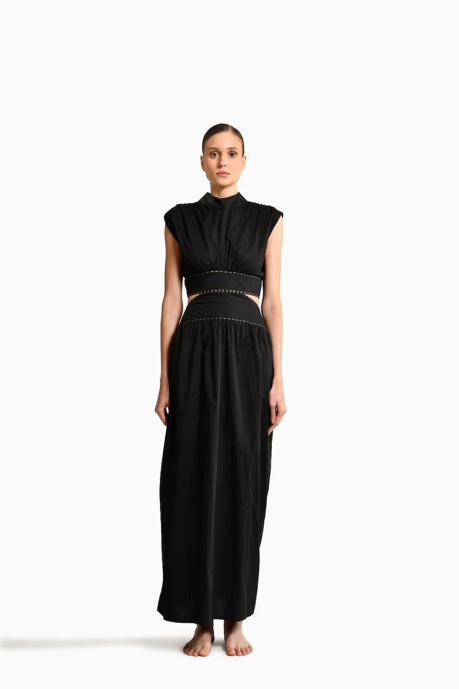 Model wearing Toya Maxi Dress with Side Cutouts, mockneck and gold stitching around waist on plain white background