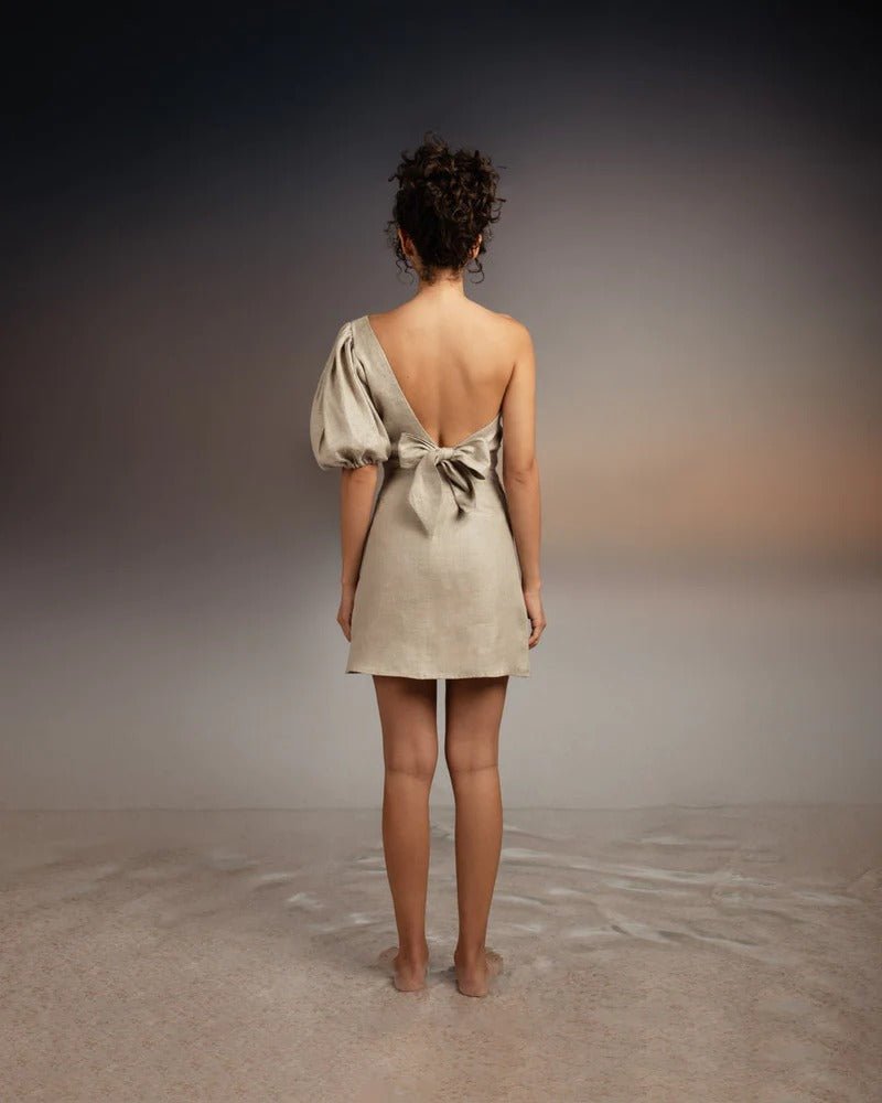 Back of model wearing Tutti Kalua Dress and standing on sand with an abstract background
