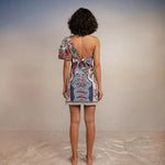 Back of model wearing Tutti Pampa Dress, standing on sand with gradient background