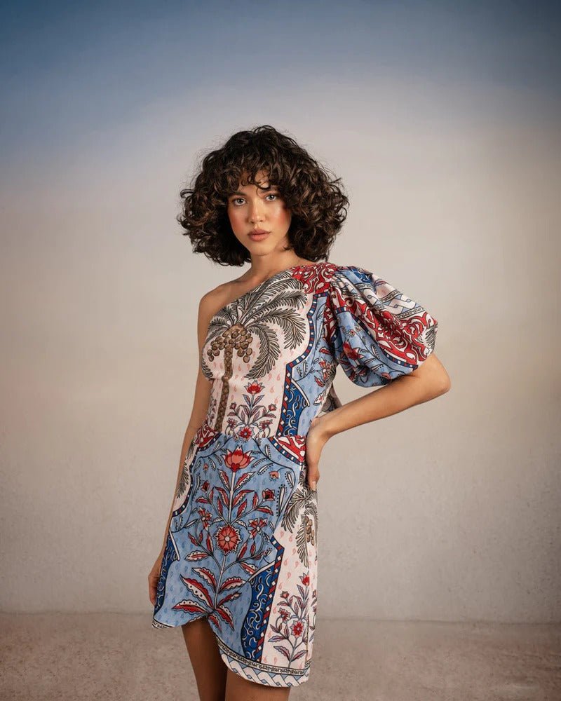 Model posing with arm on her hip, wearing Tutti Pampa Dress, standing on sand with gradient background