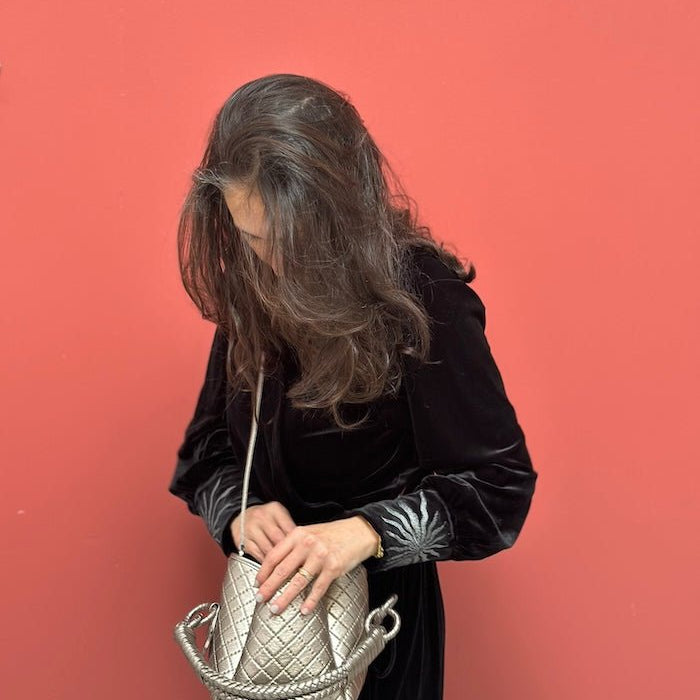 Juliana looking down wearing the velvet kimono paired with the mini tulip bag in silver