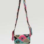 A multicolored floral patterned Wayuu crossbody carriel  bag with a pink strap and fringe detailing.