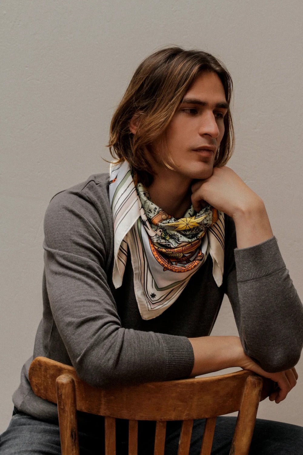 Man modeling brown zodiac scarf wrapped around neck.