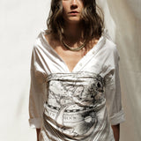 Woman modeling white zodiac scarf wrapped as Classic Bandana Top over a white long button up shirt.