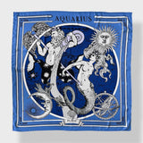 Zodiac Scarf for Aquarius by Plissé. Image of water bearer, mermaid, sun, moon, and the eliptic. The blue scarf is pictured on a white background.