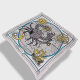 Zodiac scarf for Cancer by Plissé. Off white colored scarf with image of crab, astrological background, sun and moon details. Scarf floating on plain white background.