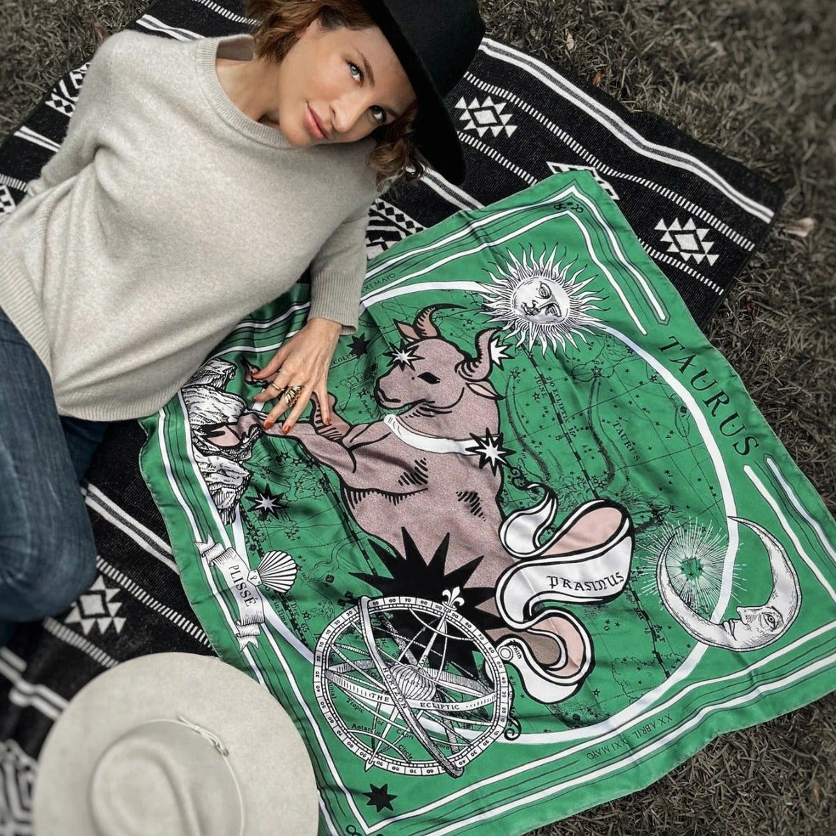Woman posing laying down next to taurus scarf