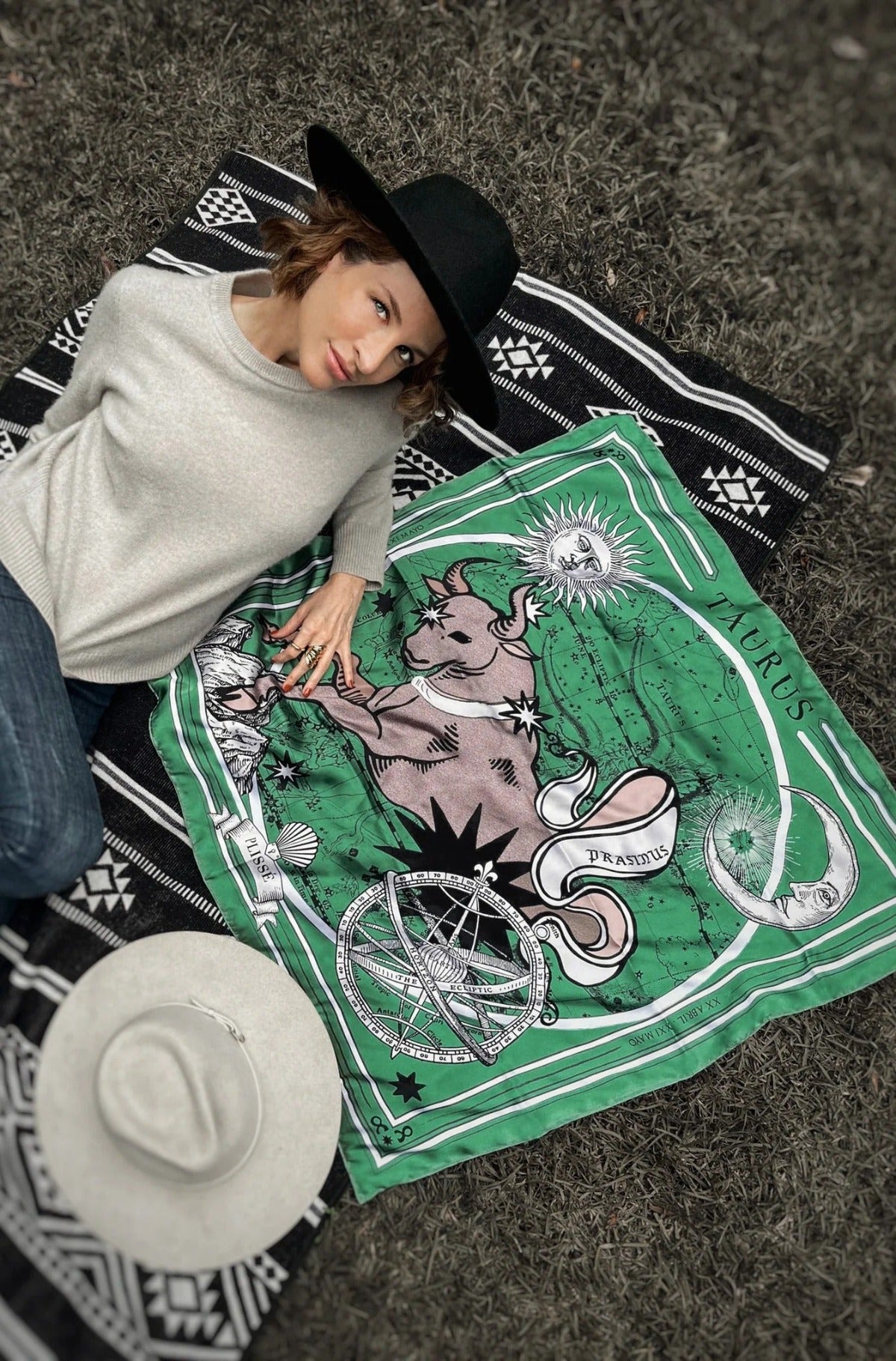 Woman posing laying down next to taurus scarf